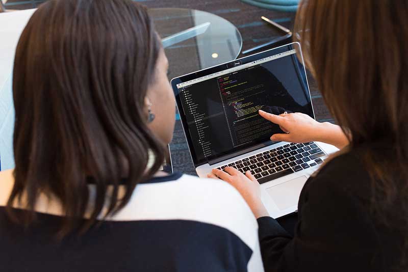 Two people working on code on a laptop