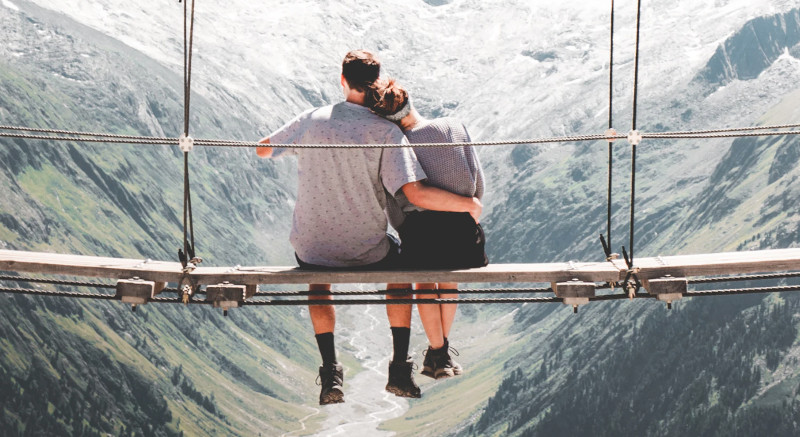 Couple sitting on a bridge in a scenic locale