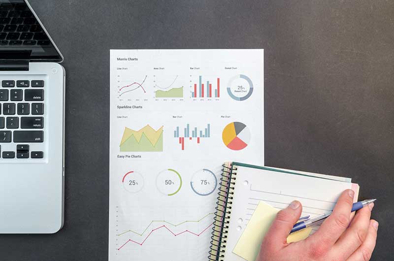 Person's hand rests on a notebook and paper with data science charts