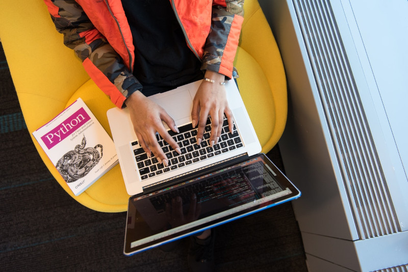 Person with Python coding book and laptop