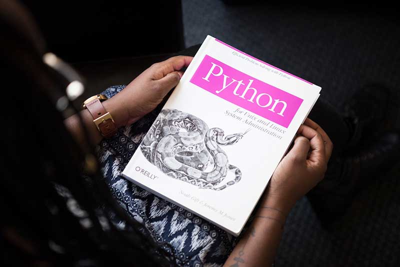 Person holding a book about Python programming language