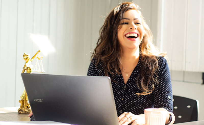 Woman laughing while on laptop